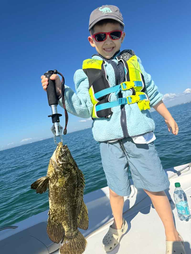A family day on the water — a kid holding a fish on a Sarasota inshore charter