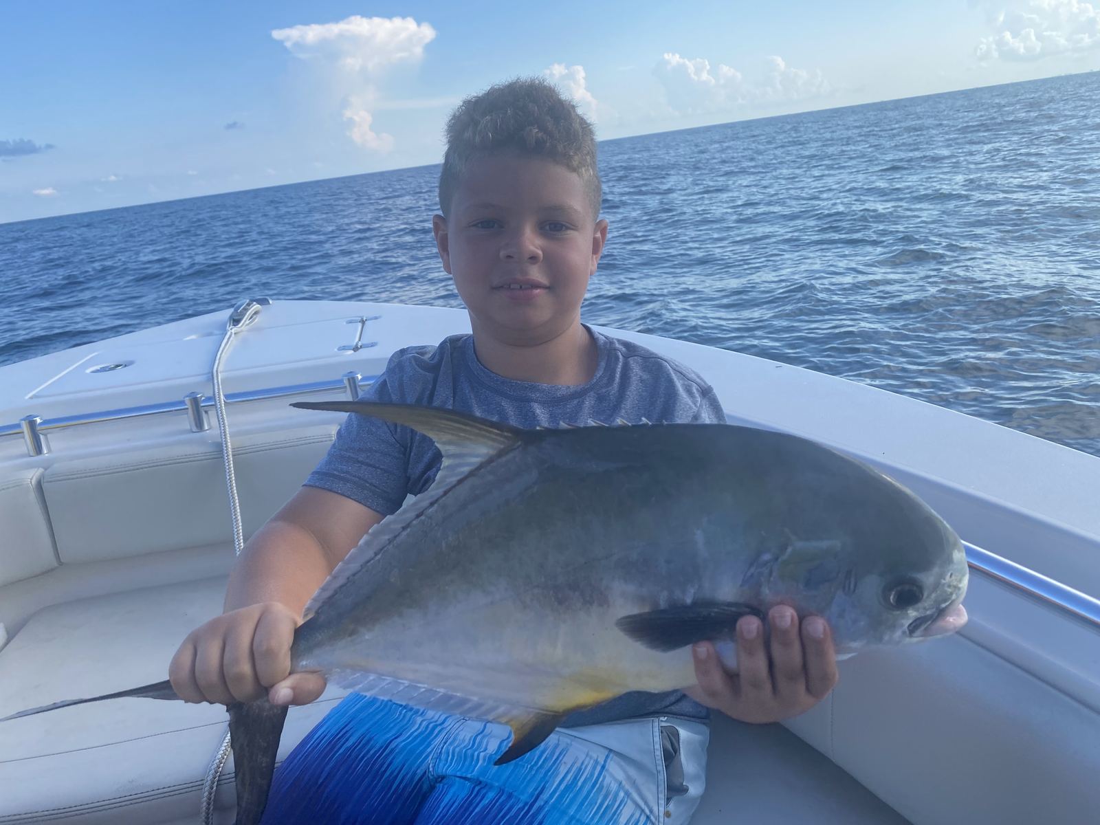 A young angler holding a permit boat-side